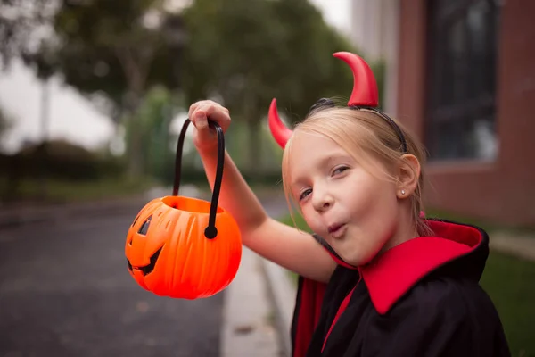 Dziewczynka w kostiumie diabła z czerwonymi rogami w parku. Szczęśliwego Halloween koncepcja — Zdjęcie stockowe