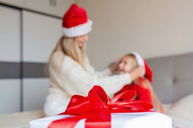 Mutlu Noeller ve mutlu yıllar. Mutlu bir anne ve yatakta tatlı bir kız çocuğu. Ebeveynler ve küçük çocuklar Coronavirus covid-19 karantinası sırasında evde eğleniyorlar. Odasında hediyeler olan sevgi dolu bir aile.