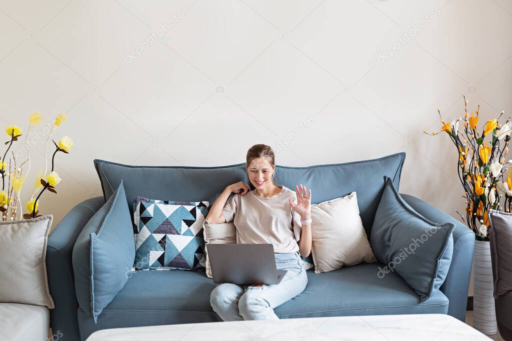 Young beautiful woman stylish wearing on gray textile sofa at home. Attractive slim female in domestic situation, staying home, resting on couch in her apartment. Background, copy space, close up.