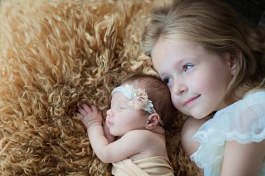 Küçük beyaz kız ve yeni doğmuş kız kardeşi. Küçük çocuk yeni kardeşle tanışıyor. Şirin bir kız ve yeni doğmuş bir bebek ev yatak odasında rahatlar. Evde iki çocuklu bir aile. Aşk, güven ve şefkat kavramı