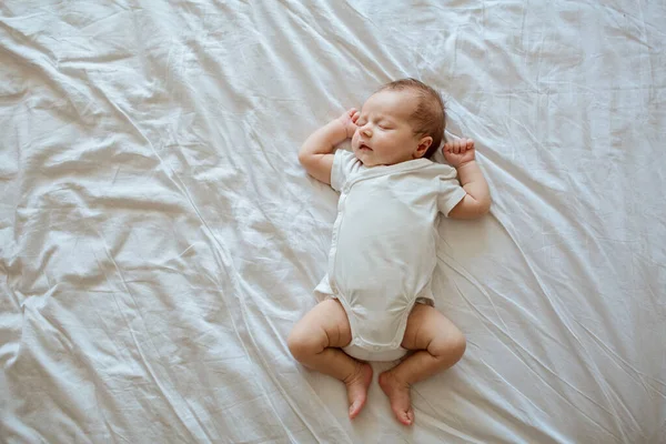 Üç haftalık şirin bir bebek beyaz bir battaniyenin üzerinde yatıyor. Bebek eşyaları paketleme şablonu. Yeni doğan bebeğin yakın plan portresi. Sağlıklı ve tıbbi konsept.