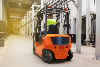 Modern otomatik depoda forklift üzerinde çalışan üniformalı bir depo çalışanı. Kutular ambarın raflarında. Depo, makine konsepti. Stokta lojistik.