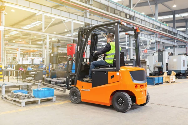 Modern otomatik depoda forklift üzerinde çalışan üniformalı bir depo çalışanı. Kutular ambarın raflarında. Depo, makine konsepti. Stokta lojistik.