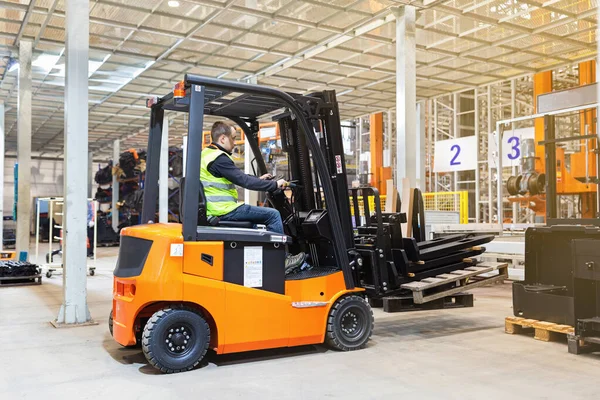 Modern otomatik depoda forklift üzerinde çalışan üniformalı bir depo çalışanı. Kutular ambarın raflarında. Depo, makine konsepti. Stokta lojistik.