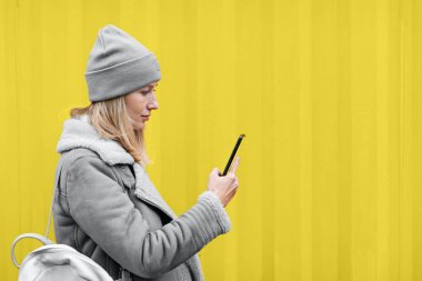 Dışarıda cep telefonu kullanan bir kadın. 2021 yılının renkleri: nihai gri ve aydınlatıcı. Renk konsepti, kopyalama alanı ile modelleme