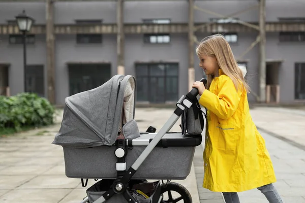 Klein blank meisje met blond haar wandelen met pasgeboren baby broer of zus buiten. Kleuren van het jaar 202: ultiem grijs en verhelderend — Stockfoto