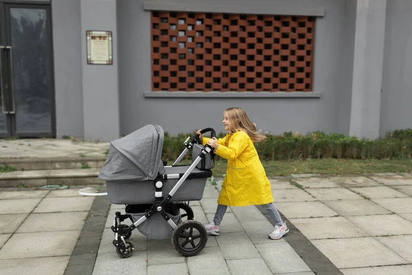 Klein blank meisje met blond haar wandelen met pasgeboren baby broer of zus buiten. Kleuren van het jaar 202: ultiem grijs en verhelderend — Stockfoto