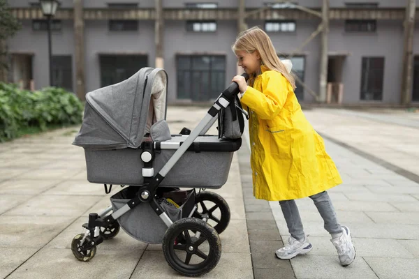 Klein blank meisje met blond haar wandelen met pasgeboren baby broer of zus buiten. Kleuren van het jaar 202: ultiem grijs en verhelderend — Stockfoto