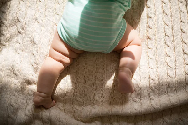 Kaukasisches Baby sechs Monate alt auf kuscheliger Strickdecke zu Hause liegend. Kind trägt süße grüne Kleidung — Stockfoto