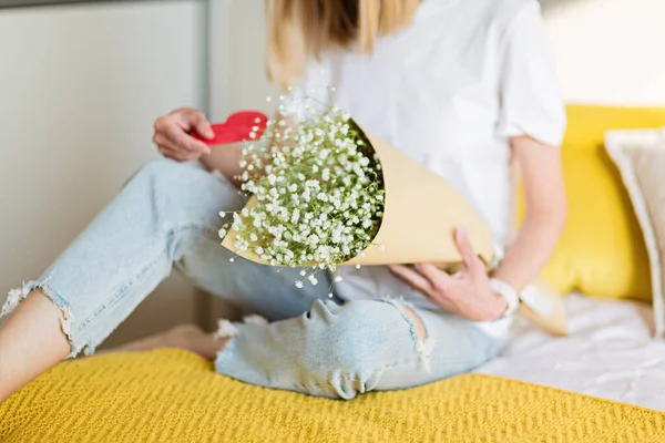 Bella giovane donna caucasica che tiene mazzo di fiori in camera da letto. Buon San Valentino. rapporto lontano e concetto di amore — Foto Stock