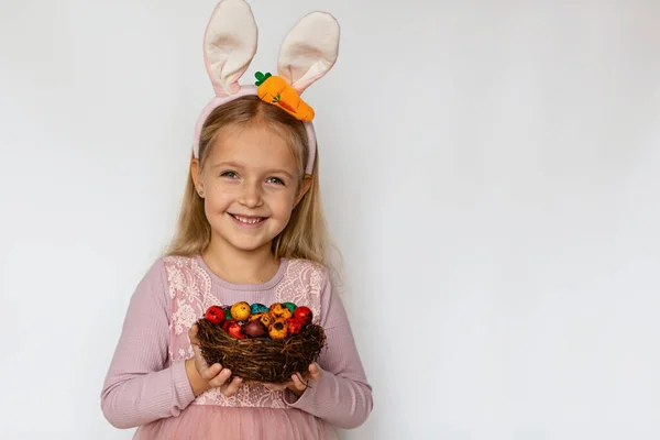 Linda niña con orejas de conejo sosteniendo huevo de Pascua, aislado sobre fondo blanco. Adorable niño celebrar vacaciones de Pascua — Foto de Stock