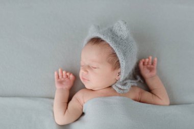Gri battaniyenin üzerinde uyuyan yeni doğmuş şirin bir bebek. Bebek eşyaları paketleme şablonu. Sağlıklı ve tıbbi konsept. Boşluğu kopyala