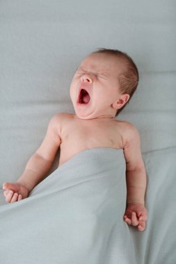 Gri battaniyenin üzerinde uyuyan yeni doğmuş şirin bir bebek. Bebek eşyaları paketleme şablonu. Sağlıklı ve tıbbi konsept. Boşluğu kopyala