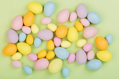 Renkli paskalya yumurtaları ve yeşil arka planda izole edilmiş pastel renkleri olan şık bir arka plan. Düz konum, üst görünüm, model, genel görünüm, şablon