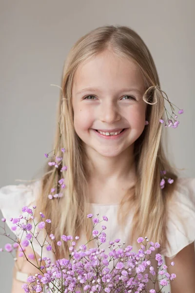 Portret uśmiechniętej białej dziewczynki z cygańskimi kwiatami odizolowanej na szarym tle. Modelka w studio. Modny pomysł twórczy — Zdjęcie stockowe