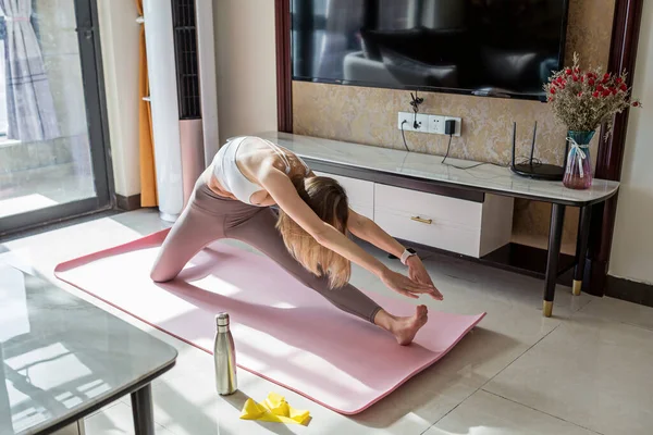 Leende passform yogatränare, glad ung sportig yogalärare liggande på mattan hemma. Home workout under Coronavirus covid-19 pandemisk karantän — Stockfoto