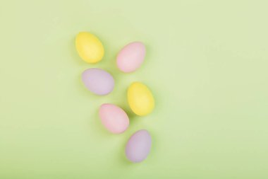 Renkli paskalya yumurtaları ve yeşil arka planda izole edilmiş pastel renkleri olan şık bir arka plan. Düz konum, üst görünüm, model, genel görünüm, şablon