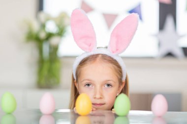 Güzel küçük kız tavşan kulağı takıyor ve Coronavirus covid-19 salgını sırasında evde paskalya yumurtası taşıyor.. 
