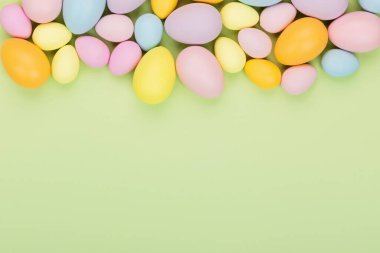 Renkli paskalya yumurtaları ve yeşil arka planda izole edilmiş pastel renkleri olan şık bir arka plan. Düz konum, üst görünüm, model, genel görünüm, şablon