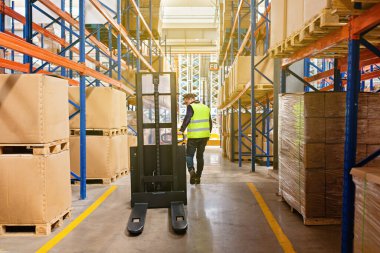 Modern otomatik depoda forklift üzerinde çalışan üniformalı bir depo çalışanı. Kutular ambarın raflarında. Depo, makine konsepti. Stokta lojistik.