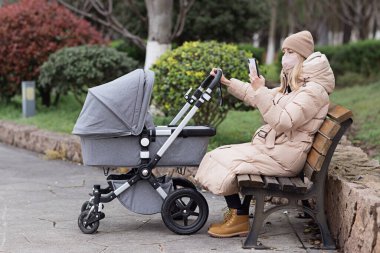 Coronavirus covid-19 salgını yüzünden yeni doğmuş bebekle yürüyen beyaz bir anne. Çevrimiçi çalışan iş kadını, cep telefonu kullanan, sosyal medya kullanan