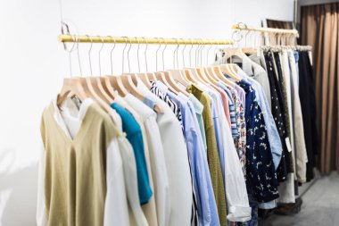 Alışveriş merkezindeki hipster moda defilesinde askıda duran farklı kadın kıyafetleri. Modayı takip eden kadınlar