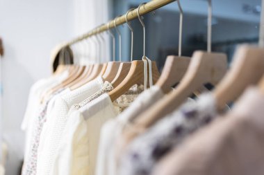 Alışveriş merkezindeki hipster moda defilesinde askıda duran farklı kadın kıyafetleri. Modayı takip eden kadınlar