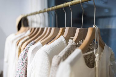 Alışveriş merkezindeki hipster moda defilesinde askıda duran farklı kadın kıyafetleri. Modayı takip eden kadınlar