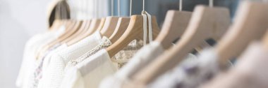 Alışveriş merkezindeki hipster moda defilesinde askıda duran farklı kadın kıyafetleri. Modayı takip eden kadınlar