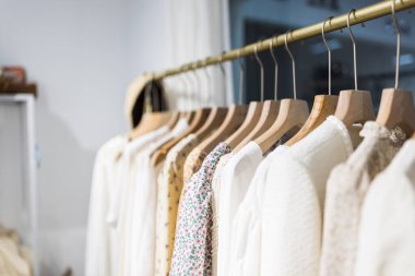 Alışveriş merkezindeki hipster moda defilesinde askıda duran farklı kadın kıyafetleri. Modayı takip eden kadınlar