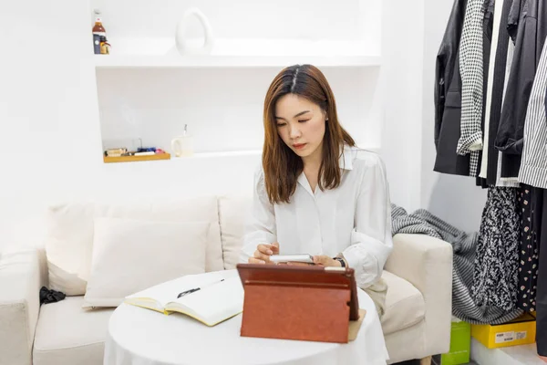 Küçük bir iş kurun, akıllı telefon ya da tablet kullanan Çinli genç girişimci paket ürün kutusu hazırlamak için online alışveriş siparişlerini alıp kontrol edin. çevrimiçi satış kavramı