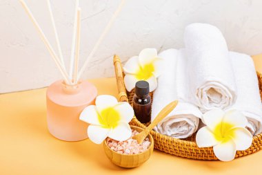 Spa masajı, vücut bakımı geçmişi. Kaplıca topları, kozmetik ürünleri, havlu ve turuncu masada tropikal çiçekler. Üst manzara, düz yatış, genel giderler, kopyalama alanı. Güzellik ve sağlık hizmetleri kavramı
