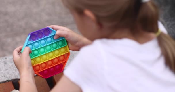 Dítě hrající si s duhou pop it fidget toy outdoor. Push bublina smyslová hračka - omyvatelný a opakovaně použitelný silikonový odlehčovací hračka. Dívka hraje s anti stres jednoduché dolíčky hračka. — Stock video