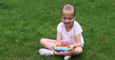 Çocuk dışarıda gökkuşağıyla oynuyor. Kıpır kıpır. Baloncuklu duyusal oyuncağı kullan. Yıkanabilir ve yeniden kullanılabilir silikon stres giderici oyuncak. Küçük kız stres önleyici, basit gamzeli oyuncakla oynuyor.. 