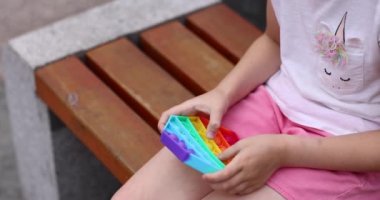 Çocuk dışarıda gökkuşağıyla oynuyor. Kıpır kıpır. Baloncuklu duyusal oyuncağı kullan. Yıkanabilir ve yeniden kullanılabilir silikon stres giderici oyuncak. Küçük kız stres önleyici, basit gamzeli oyuncakla oynuyor.. 