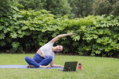 Genç Kafkas Kadın COVID-19 Coronavirus salgını sırasında internette egzersiz yapıyor. Fitness antrenmanında sosyal mesafeler. Esneme ve yoga yaparken spor giyen bir kız.