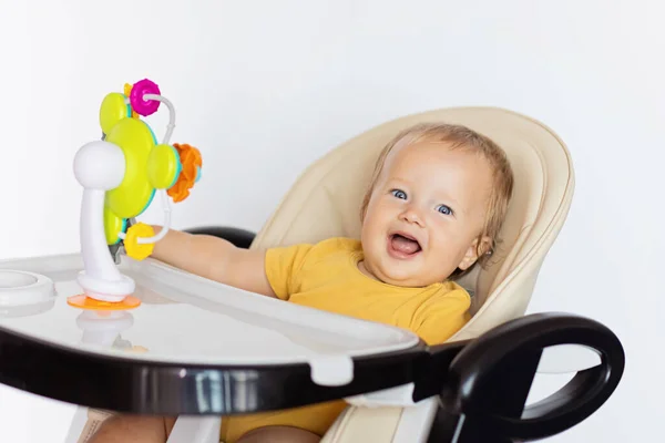 Bonito menina branca bebê dez meses de idade sentado em cadeira de bebê e brincando com brinquedo plástico colorido educacional isolado no fundo branco — Fotografia de Stock