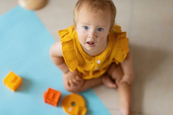 Küçük beyaz kız on aylık evde ya da çocuk odasında eğitici silikon oyuncaklarla oynuyor. Beyaz arka planda renkli oyuncaklarla eğlenen çocuk — Stok fotoğraf