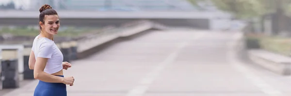 Joven morena corriendo por carretera de asfalto en el parque de verano. Activa atlética hembra caucásica tiene entrenamiento matutino. Persona atlética en ejercicios de ropa deportiva al aire libre. Leggins vestidos y top deportivo —  Fotos de Stock