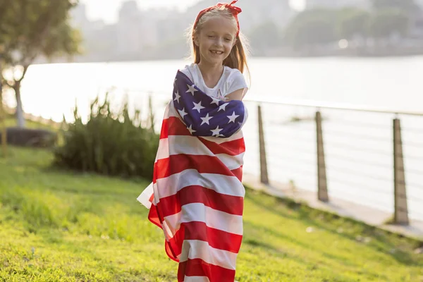 Patriotic holiday. Happy family, mother and daughter with American flag outdoors on sunset. USA celebrate independence day 4th of July. — Stock Photo, Image