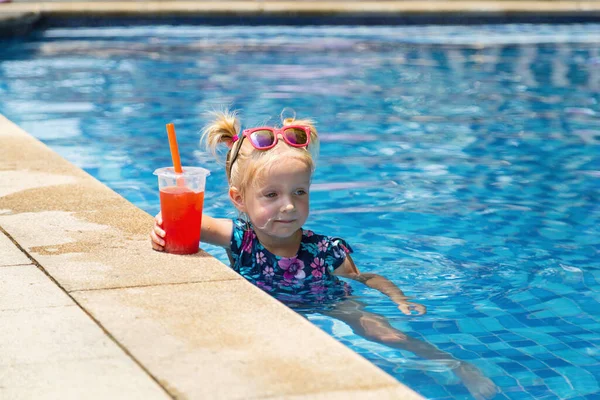 Menina branca pequena feliz com óculos de sol sorrindo alegremente e desfrutando de férias de verão tempo na piscina no hotel resort. Criança com cabelo loiro vestindo roupa de banho durante as férias de verão — Fotografia de Stock