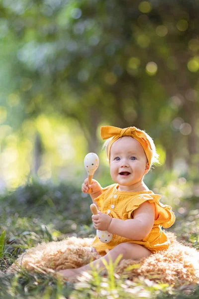 Portret uroczej białej dziewczynki sprzed 10 miesięcy bawiącej się w letnim parku. Stylowe niemowlę z blond włosami i niebieskimi oczami w modnej odzieży. Szczęśliwego dzieciństwa i opieki zdrowotnej dla dzieci — Zdjęcie stockowe