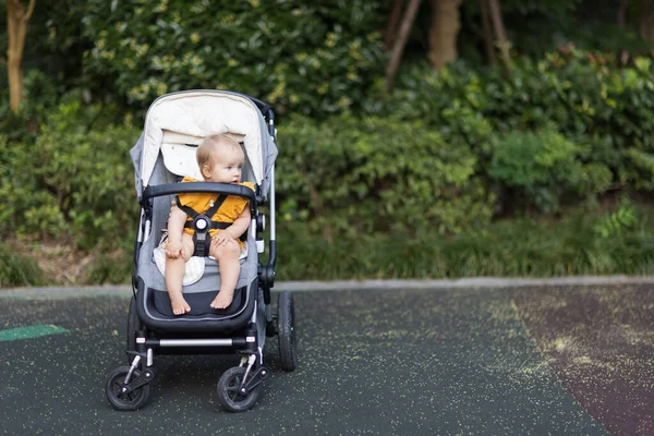 Een lief blank meisje van tien maanden in een kinderwagen buiten. Klein kind in kinderwagen. Het kleine kind zit in een kinderwagen. Zomer wandelingen met kinderen. Familie vrijetijdsbesteding met klein kind. — Stockfoto