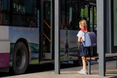 Huzhou, Çin 22 Haziran 2021: Pioneer 'de okula üniformalı ve kırmızı kravatlı mutlu beyaz kız. İstasyonda bekleyen çocuk.