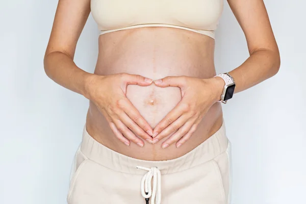 Fotografía de cerca de la joven mujer tocando las manos de su gran vientre desnudo Aislado sobre fondo blanco con espacio de copia. Cuidado de la piel con crema hidratante contra las estrías. Embarazo emocional amoroso — Foto de Stock