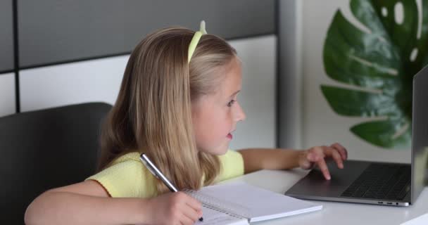 Étudiante caucasienne de petite fille étudiant en ligne de la maison, regardant la leçon de classe Web ou écoutant tuteur par appel vidéo elearning pendant coronavirus covid-19 isolement auto pandémique. Mouvement lent — Video