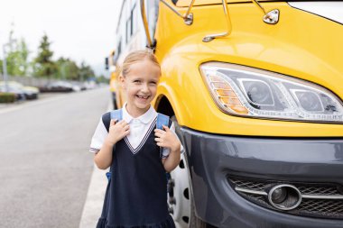 Okula dönelim. Sarı otobüsün yanındaki ilkokuldan küçük bir kız. Çocuk 1 Eylül 'de yeni şeyler öğrenecek.