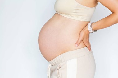 Genç bir kadının çıplak karnına dokunurken çekilmiş yakın plan fotoğrafı. Beyaz arka planda, fotokopi alanı ile izole edilmiş. Genişleme izlerine karşı nemlendirici kremle cilt bakımı. Duygusal aşk hamileliği