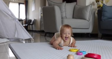 Otantik yakın plan. Beyaz bir kız bebek. Evdeki oturma odasında yerde oynuyor. Yavaş Hareket.