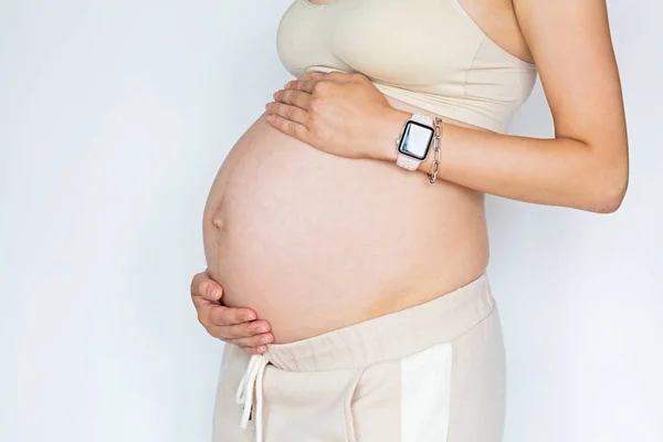 Close-up fotografie van jonge vrouw aanraken handen haar naakte grote buik Geïsoleerd op witte achtergrond met kopieerruimte. Huidverzorging met hydraterende crème tegen striae. Emotionele liefdevolle zwangerschap — Stockfoto